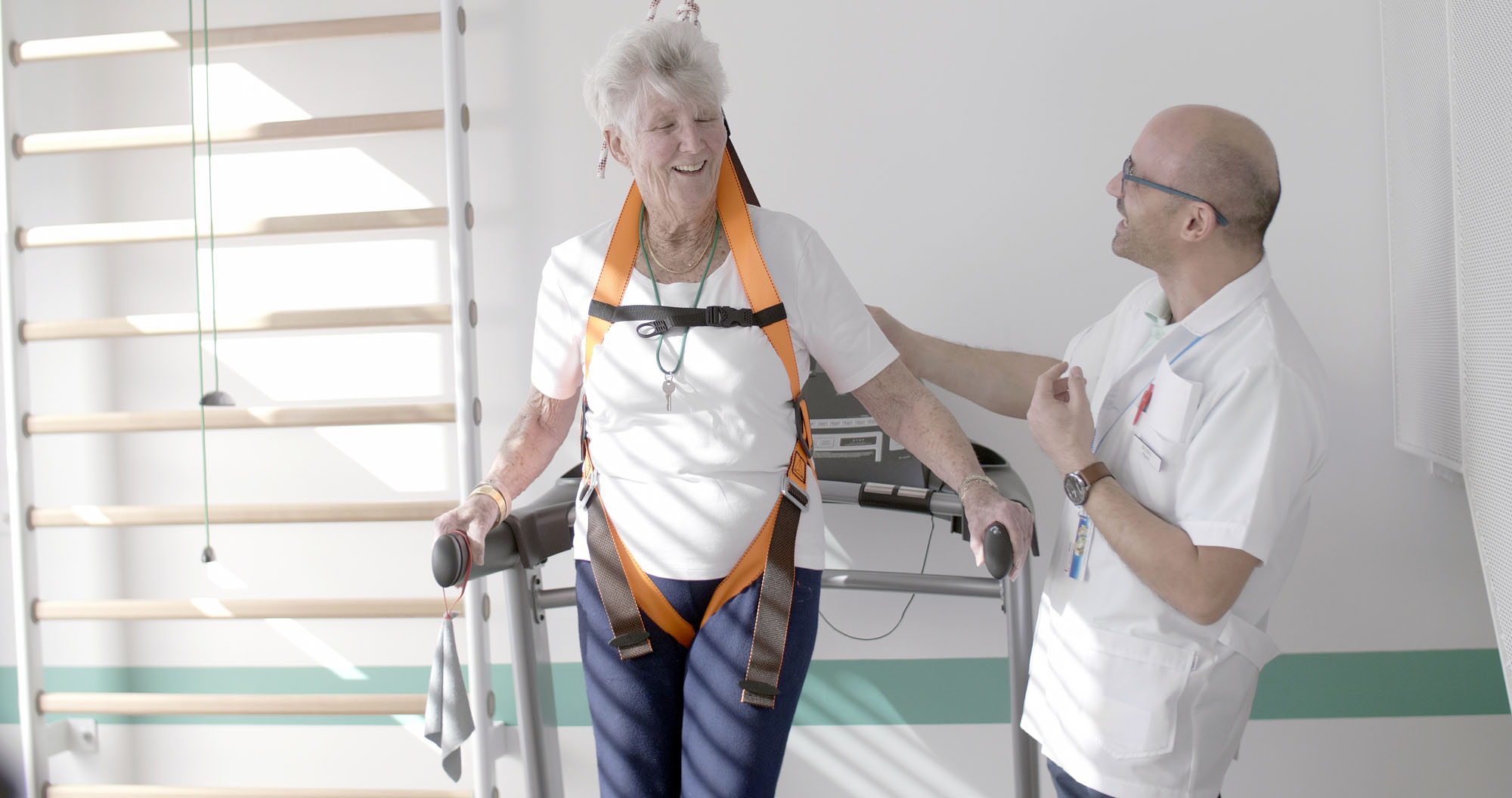 Test d'équilibre sécurisé par un harnais, encadré par un physiothérapeute au centre Dr.E.