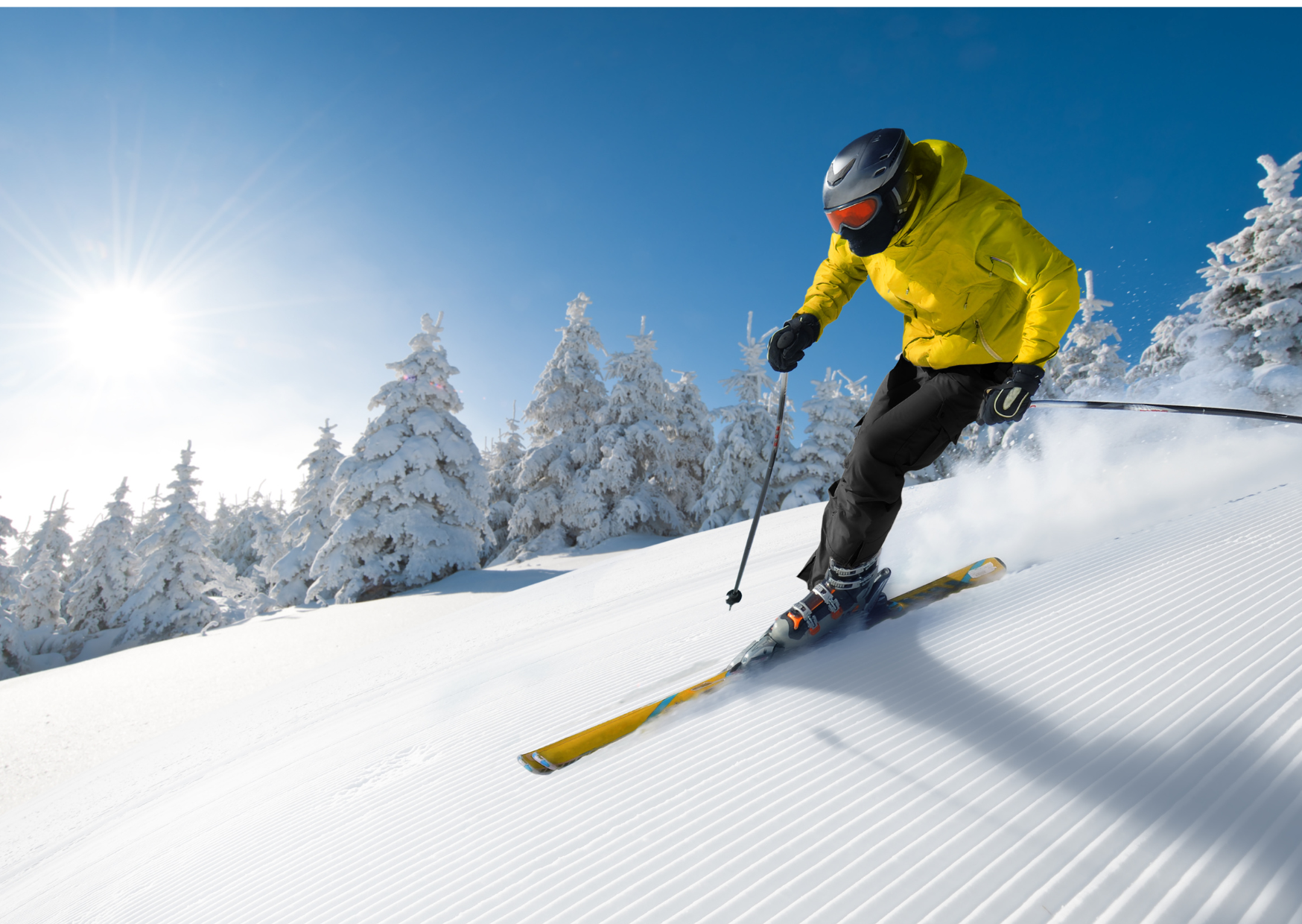 Skier in a yellow jacket descending a snowy slope